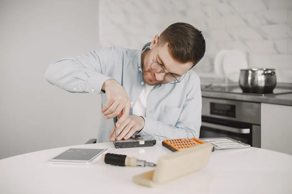 The 50% Rule for Appliance Repair: When to Repair vs Replace 2 Man in glasses using a screwdriver to repair a small kitchen appliance on a table