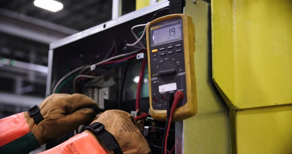 HVAC Repair Cost Guide: Capacitor, Compressor, Refrigerant Explained 3 Electrician using a multimeter to fix industrial control panel wiring.