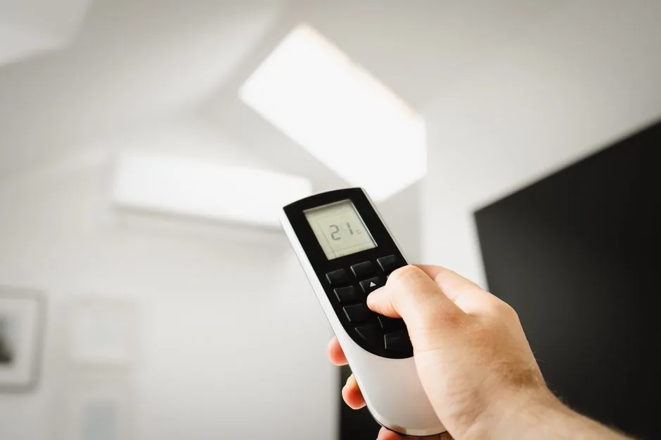 Ductless Mini-Split vs Central AC: Cost and Efficiency Compared 5 Close-up of a man using a remote to control air conditioning indoors.